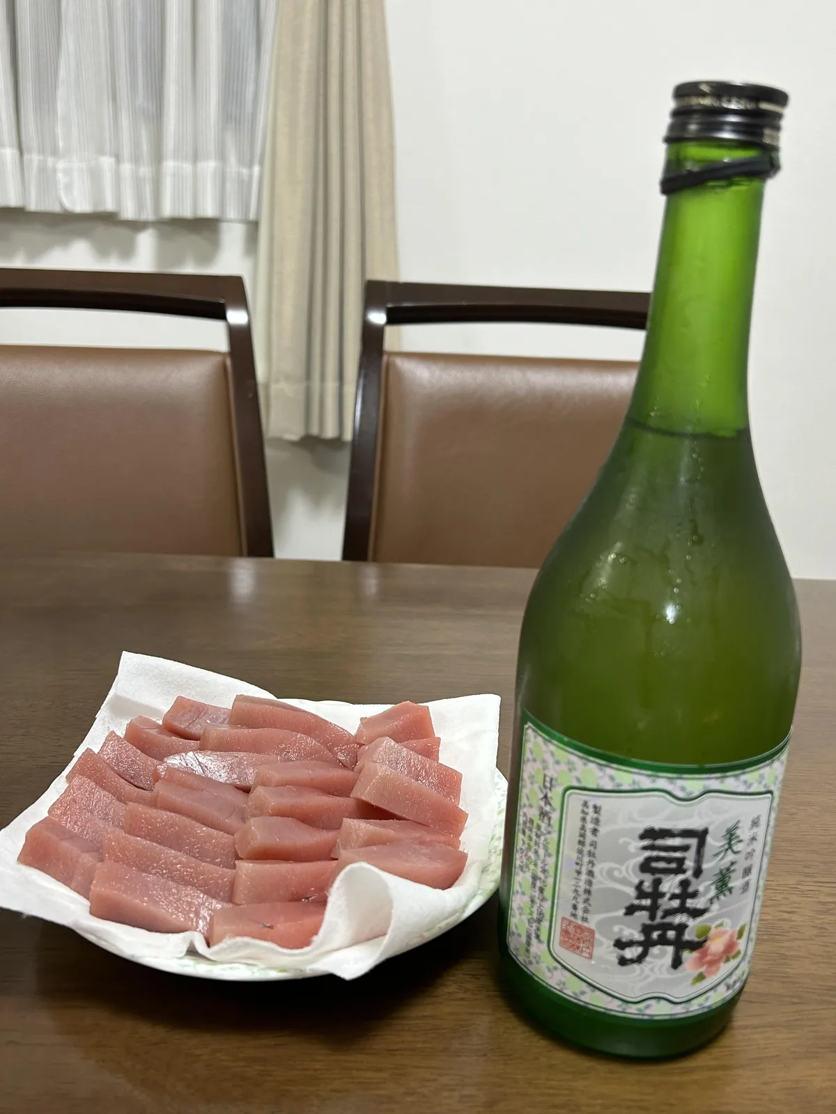 水滴のついた司牡丹 純米吟醸 美薫のボトルと、お皿にきれいに並べられた刺身
