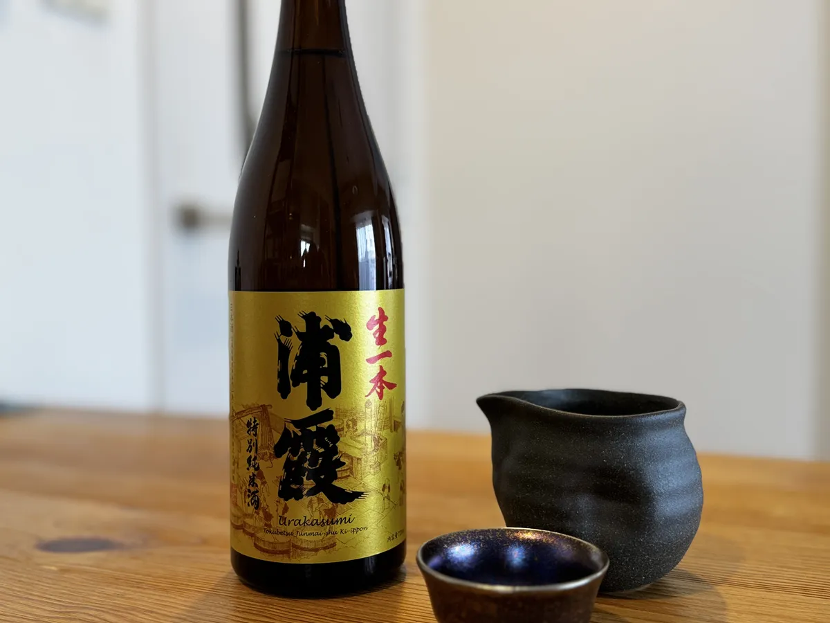 木目のテーブルに置かれた特別純米酒 生一本 浦霞のボトルと黒い酒器