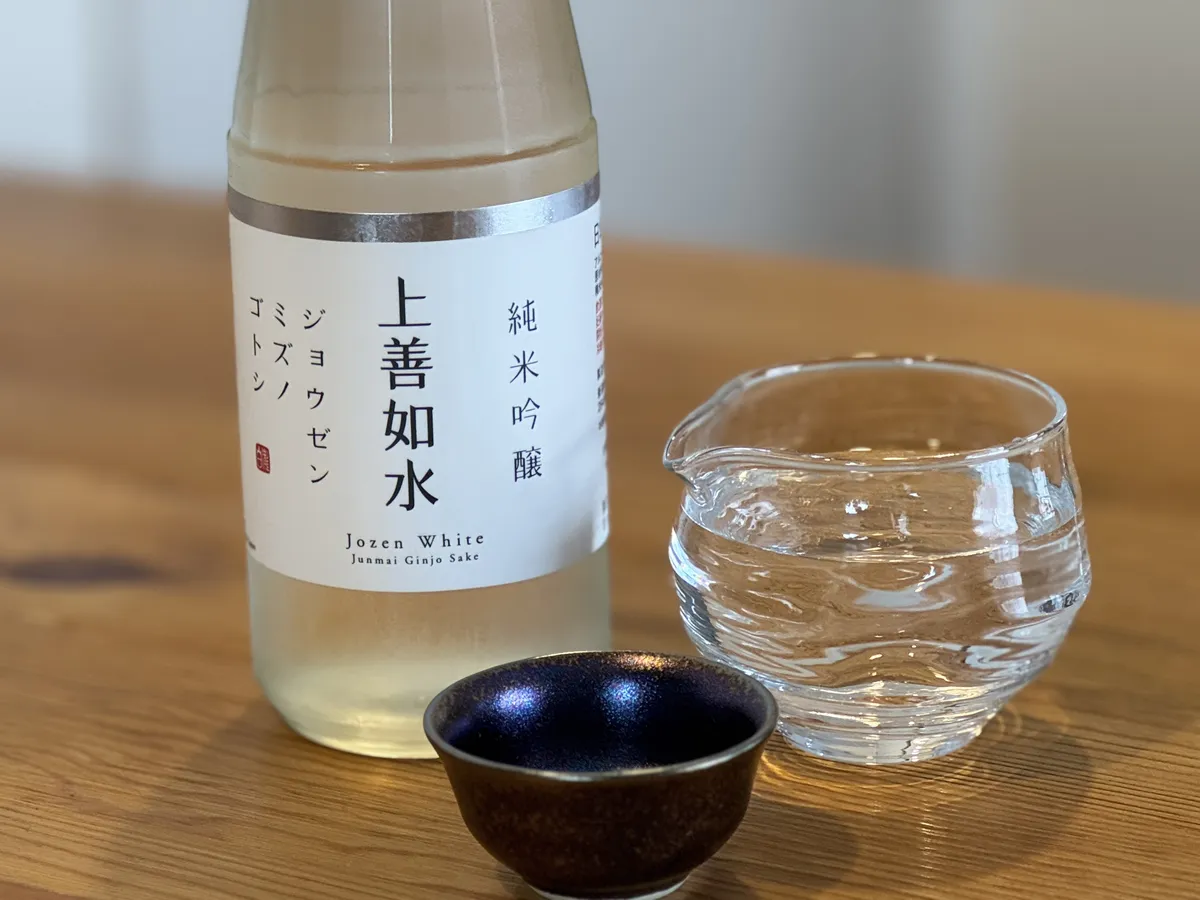 木目のテーブルに置かれた上善如水 純米吟醸のボトルと酒器